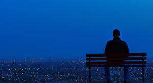 man on park bench looking over night city